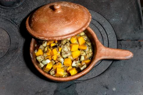 Ceramic pan with open lid that lets you see a boiling meal Stock Photos