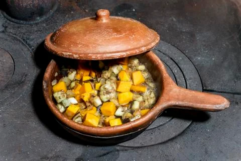 Ceramic pan with open lid that lets you see a boiling meal Stock Photos