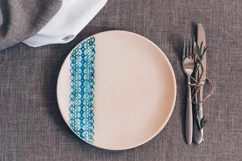 Ceramic plate with blue lace pattern on textile table setting with fork Stock Photos