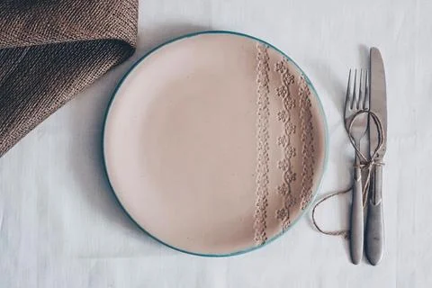 Ceramic plate with embossed floral pattern on white linen table setting with Stock Photos