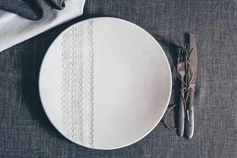 Ceramic plate with embossed lace pattern on gray textile table setting with Stock Photos