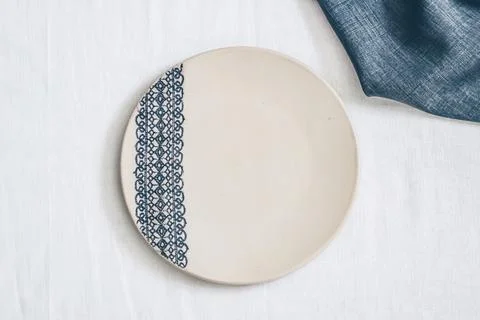 Ceramic plate with lace pattern decoration on white linen tablecloth top Stock Photos