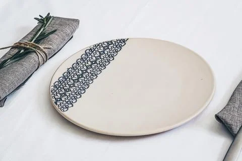 Ceramic plate with lace pattern decoration on white linen table setting with Stock Photos