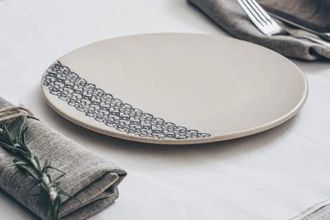 Ceramic plate on linen table setting with fork and napkin minimal rustic Stock Photos
