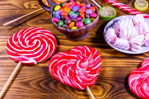 Ceramic plate with marshmallow, candy cane and lollipops on a wooden table Stock Photos