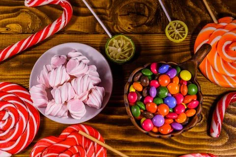 Ceramic plate with marshmallow, candy cane and lollipops on a wooden table Stock Photos