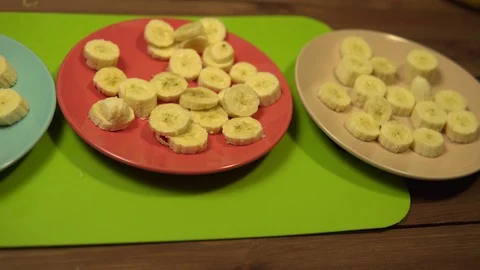 Ceramic plates with slices of bananas stand on a wooden table. Stock Footage 102447900