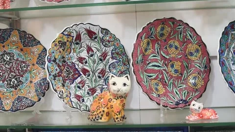 Ceramic plates with traditional national pattern lies on stall in market Stock Footage 183990371