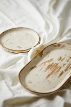 Ceramic plates on white textile background. Handmade ceramics. Stock Photos