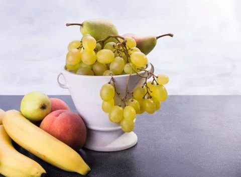 Ceramic pot full of fruit like grapes pears bananas peaches Stock Photos