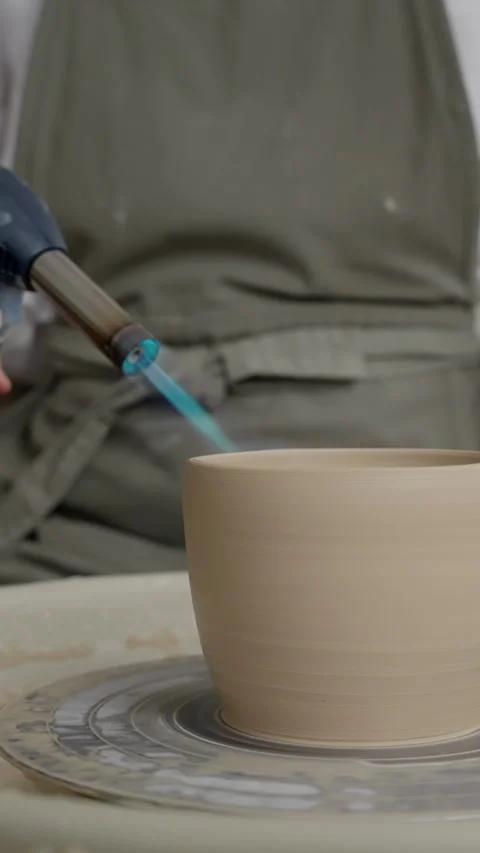 Ceramic pot on pottery wheel with flame from blowtorch, intricate pottery making Stock Footage 266673120