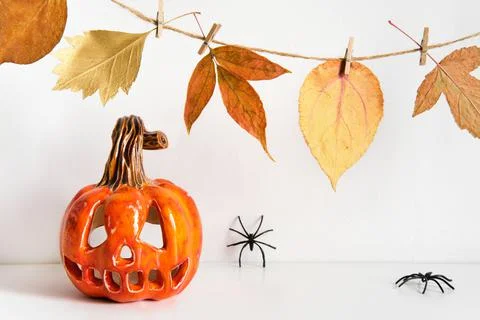 Ceramic pumpkin jack lantern and autumn leaves garland on table wall background Stock Photos