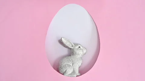 Ceramic silver rabbit appear in egg shape frame. Easter stop motion flat lay Stock Footage 171453181