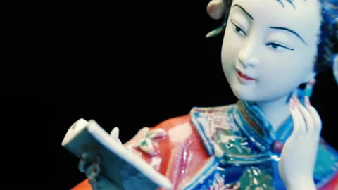 Ceramic statuette of a Chinese girl who reading a book with flowers in her hair Stock Footage 121595553