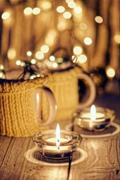 Ceramic stylish cups in sweaters and christmas retro garland on bokeh lights Stock Photos