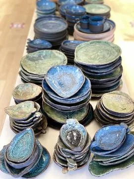 Ceramic tableware with blue green glazed finish stacked on wooden surface Foto stock