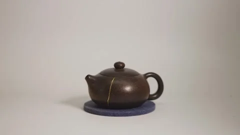 Ceramic Tea pot with a kintsugi repair gold crack on a felt pad with a Stock Footage 289176949