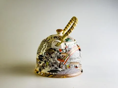 Ceramic teapot with abstract pattern and wicker straw handle on a white backg Stock Photos