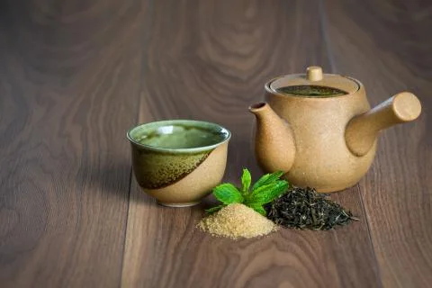 Ceramic teapot, cup of black tea with mint leaves and brown sugar Stock Photos