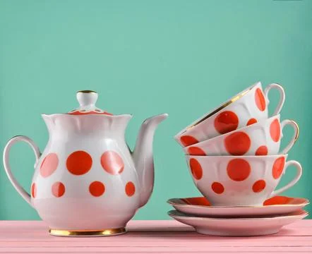 Ceramic teapot, a stack of cups in polka dots on a wooden table isolated on a Stock Photos