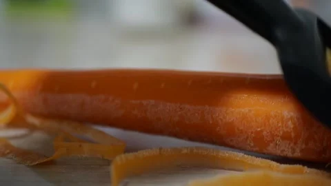 Ceramic vegetable peeler removing bright orange carrot skin crisp scrape sounds Stock Footage 320894878
