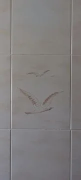 Ceramic wall tile with engraved bird design in neutral tones Stock Photos