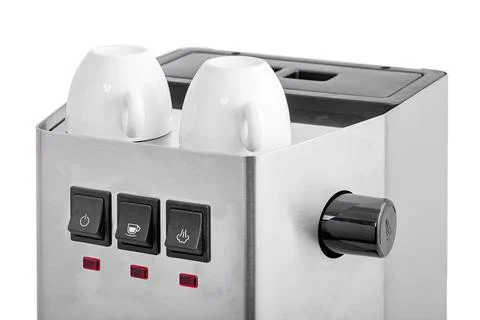 Ceramic white espresso cups stand on top of professional coffee machine. Stock Photos