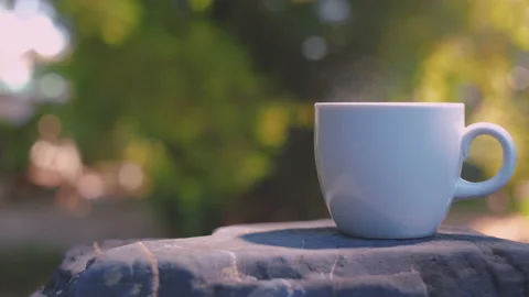 Ceramic white hot drink cup with steam on black rock floor Stock Footage 165097599