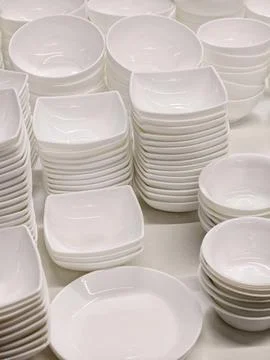Ceramic white tableware arranged in stacked sets including plates saucers a.. Foto stock
