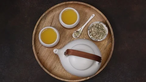 Ceramic white teapot and cups. Lemongrass tea on ceramic bowl. Brown stone ba Stock Footage 204158833