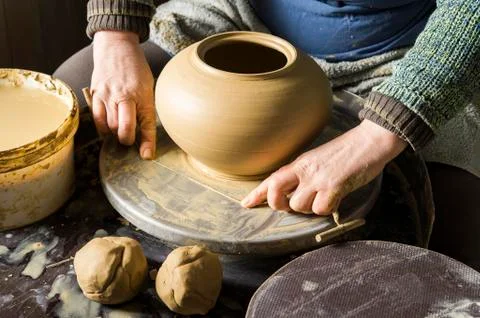 Ceramic workshop hands separate clay with cutting wire from pottery wheel Stock Photos