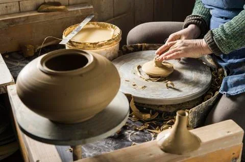 Ceramic workshop hands shaping lid of pot on pottery wheel finished pot and Stock Photos