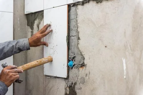 Ceramist puts tile on the wall. Professional ceramist is laying ceramic tile  Stock Photos