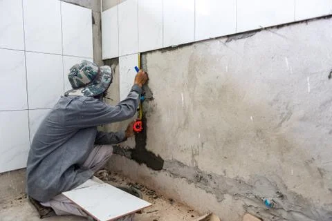 Ceramist puts tile on the wall. Professional ceramist is laying ceramic tile  Stock Photos