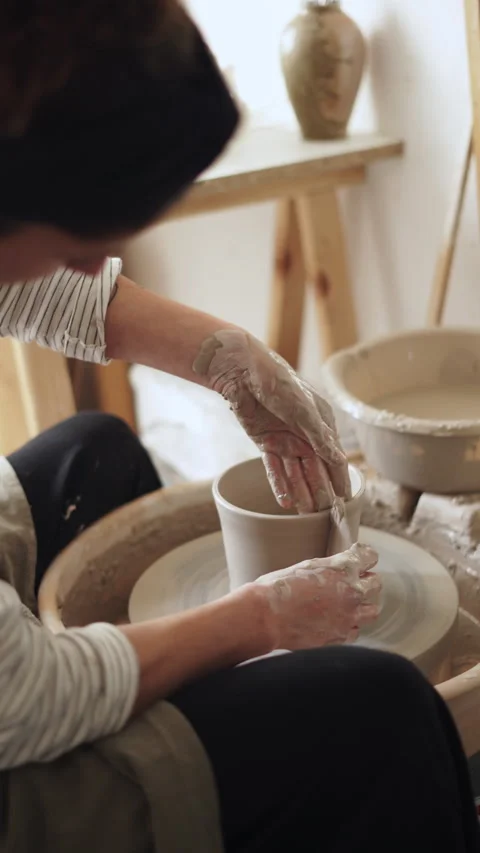 Ceramist using a wooden tool to even out a clay piece on a pottery wheel, t.. Stock Footage 272839880