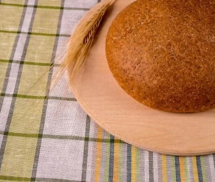 Cereal bread on a light board and ears of wheat. Stock Photos