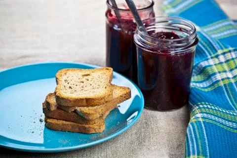 Cereal bread slices on blue ceramic plate and homemade cherry and wild berrie Stock Photos