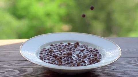 Cereal chocolate balls fall in plate with milk on rustic wooden table 스톡 동영상 76510227