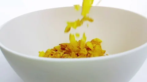 Cereal corn flakes falling down in a bowl, shot in slow motion on white Stock Footage 79153231