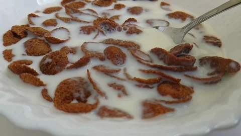 Cereal flakes against white background milk flying, spoon slow-motion Stock Footage 87945397