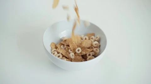 Cereals and cornflakes dropping into a white bowl in slow motion. Stockbeeldmateriaal 106141318