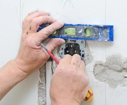 Certified electrician installing socket for light switch. Stock Photos