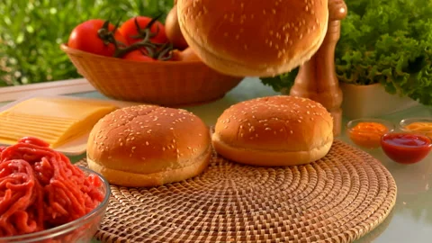 Cesam bun is falling on the table next to the ingredients for cheeseburger Stock Footage 136366160
