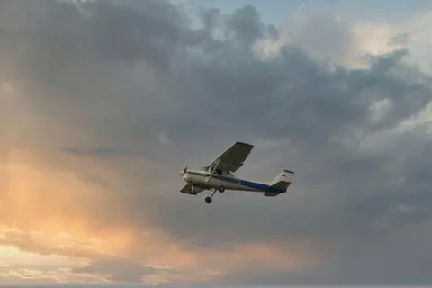 Cessna plane flying at sunset in the clouds Stock Photos