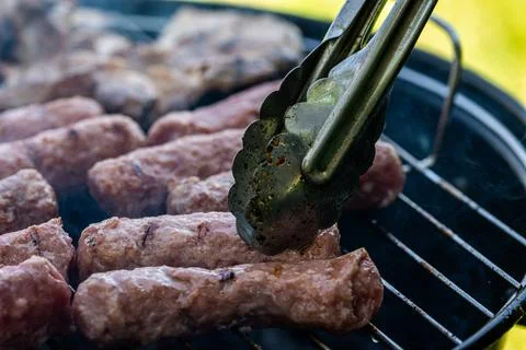 Cevapi grilling on charcoal barbecue with smoke rising from hot grill, trad.. Stock Photos