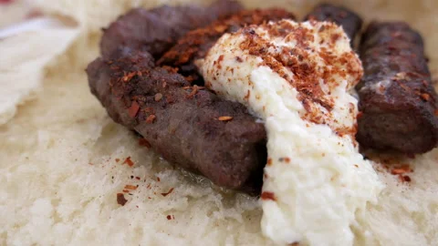Cevapi served on a bun with creamy kaymak and paprika powder. Close up Stock Footage 190567960