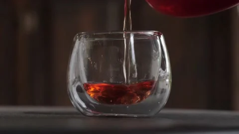 Ceylon tea pouring from teapot to fill in glass isolated on black background Stock Footage 237071787