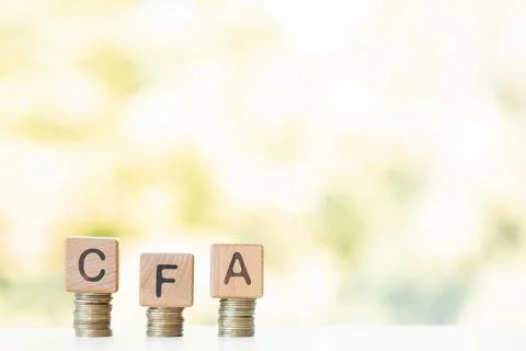 CFA word written on wood cubes, stacks of coins, nature green background. Stock Photos