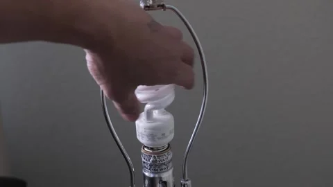 CFL light bulb installed onto a lamp Stock Footage 296998330