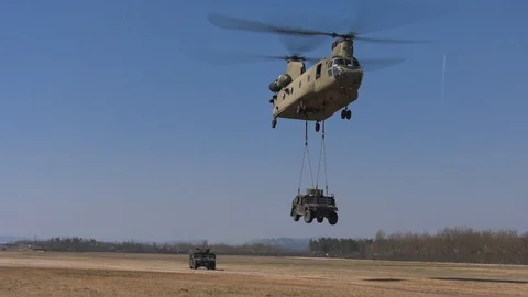  CH-47 Chinook helicopter performs a sling load carrying Humvee jeep Stock Footage 105289505